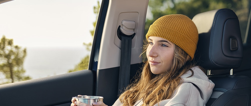 Jeune fille assise à l'avant de Citroën C5 Aircross et tenant un mug